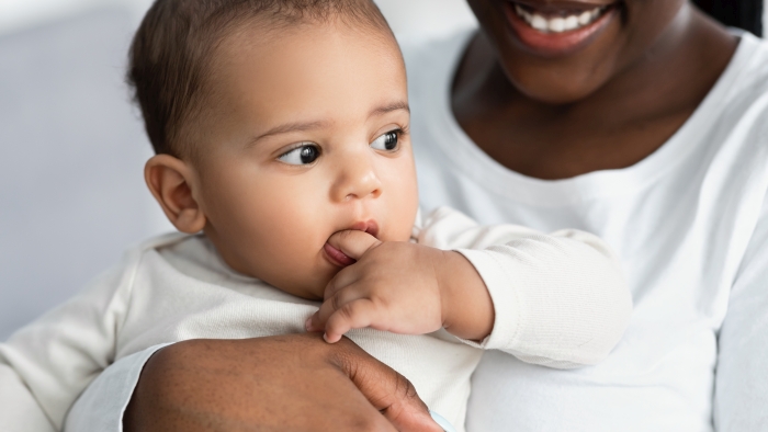 African American mom hugging her cute kid at home while checking his teeth.