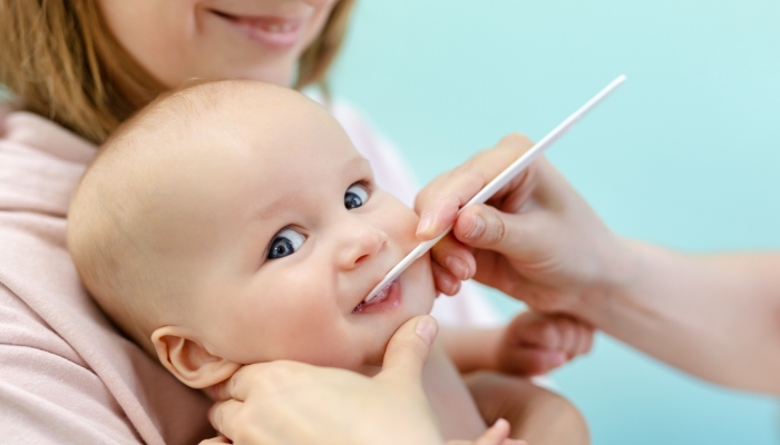 Baby on mothers hand at doctors office checking her teeth.