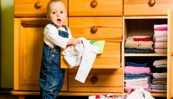 Baby throws out clothes from the storage.
