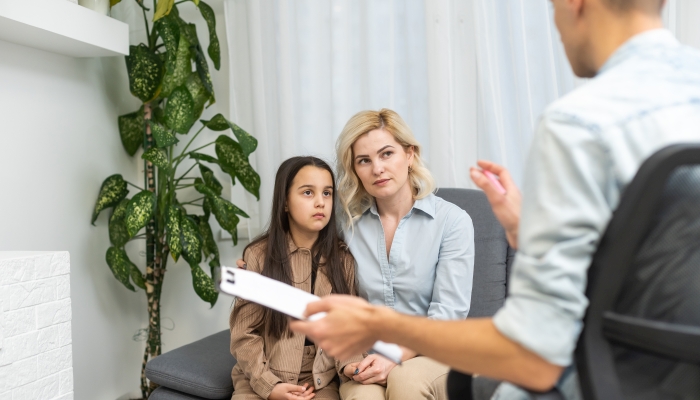 Child psychotherapist working with little girl and her mother in office.