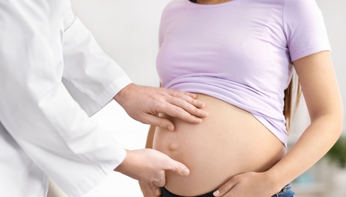 Doctor examining pregnant woman in clinic.