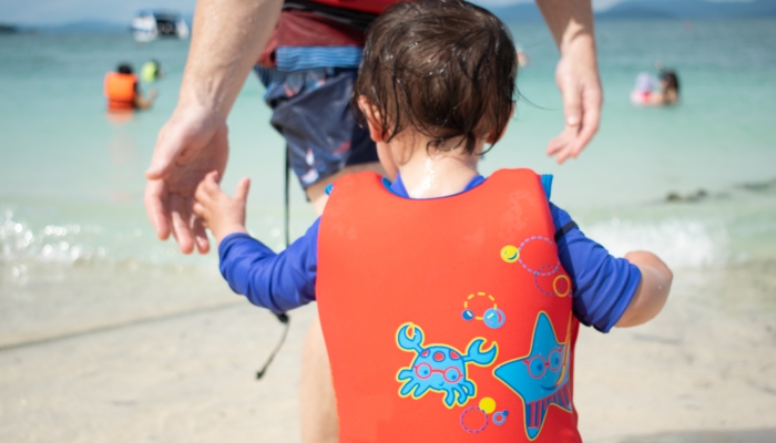 Father and baby water life vest at the beach