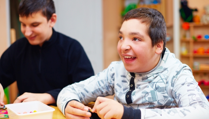 Happy kids with disability develop their fine motor skills at rehabilitation center for kids with special needs.