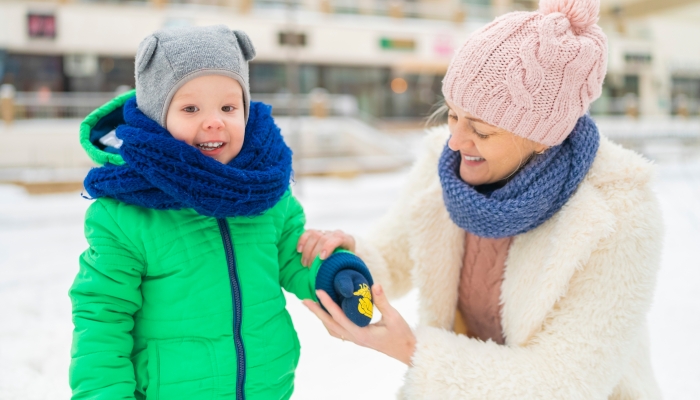 Mom puts mittens on her son and laughs around the city in winter.