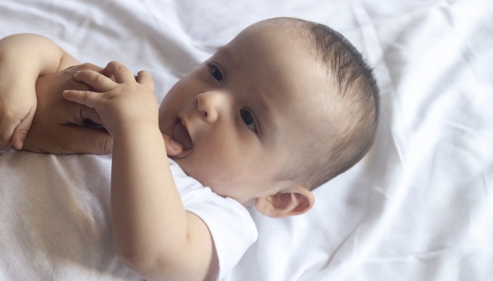 Mother checking her baby boy mouth on first signs of baby teeth come in.