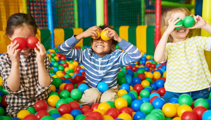 Portrait of three funny little kids playing in ball pit.