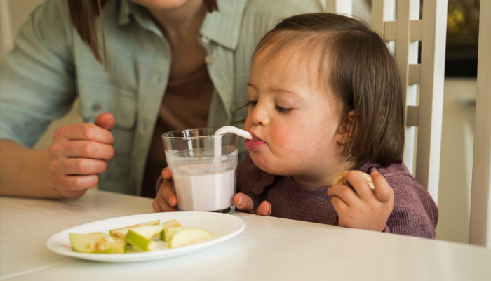 Little girl with special needs drinking from a straw.