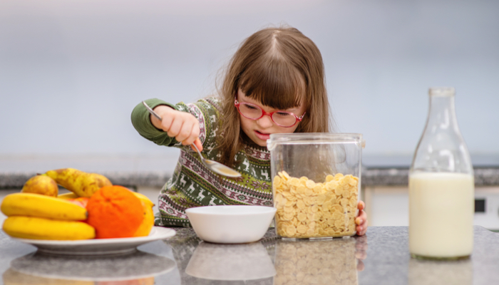 Little girl with special needs making her own breakfast.