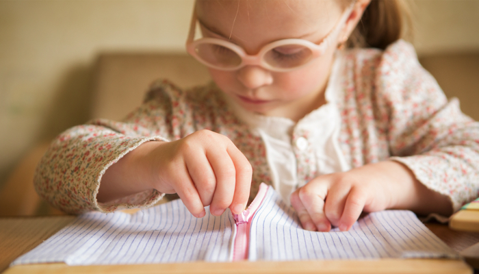 Little girl with special needs learning to use a zipper.