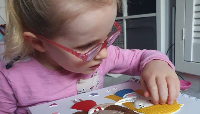 Minnie reading a Living Paintings tactile book.