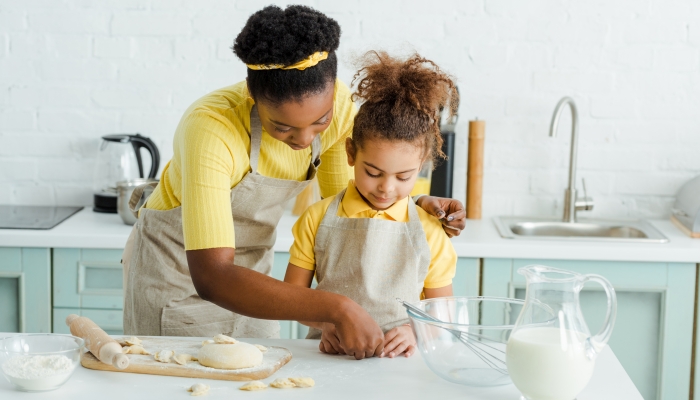 Mother with daughter sculpting dumplings in kitchen.