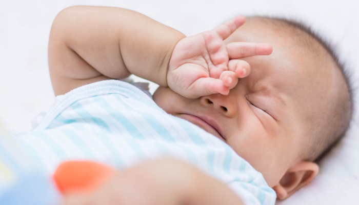 Baby rubbing it's eyes unable to sleep.