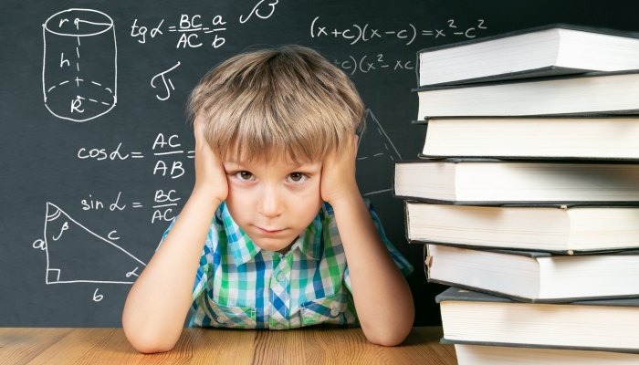 Boy trying to solve math equations in front of blackboard.