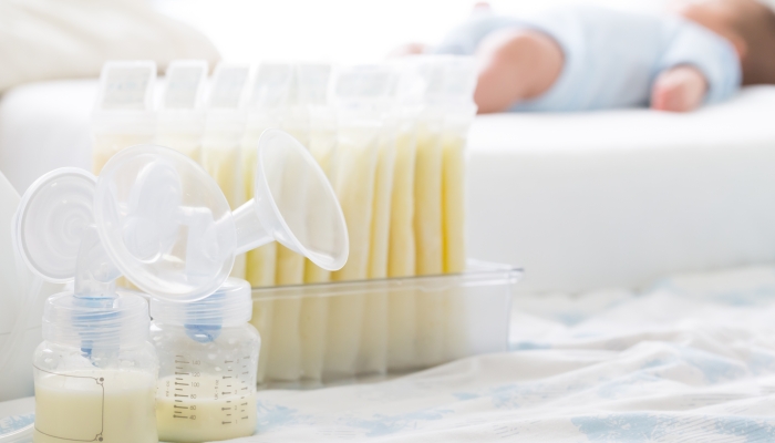 Breast milk frozen in storage bag and baby lying on background.