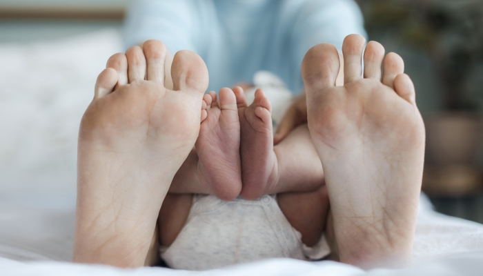 Closeup mother's and newborn's feet at home.