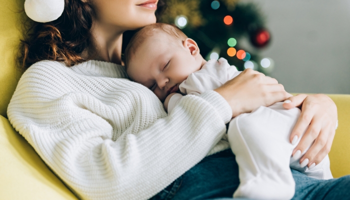 Cropped view of young mother holding sleeping baby.