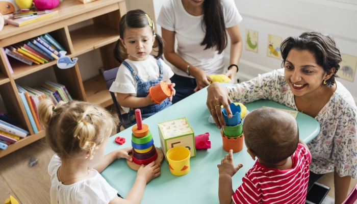 Daycare children playing with teacher in the classroom.