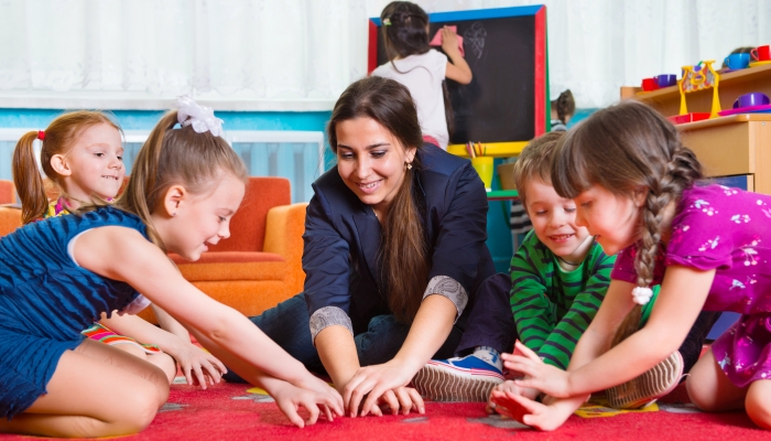 Children with tutor plaing development games at kindergarten.