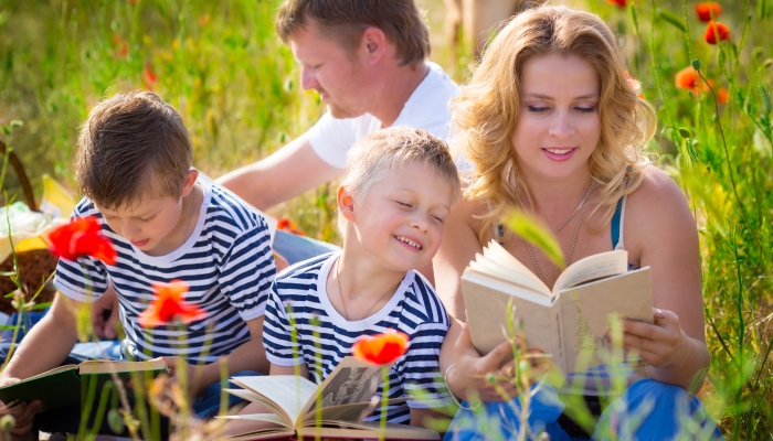 Family in the park reading books.