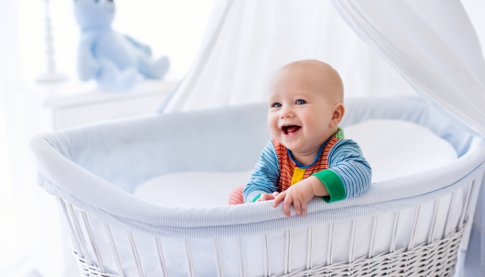 Funny baby in white bassinet with canopy.