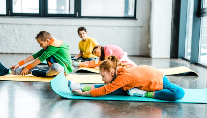 Group of kids stretching on colorful fitness mats.