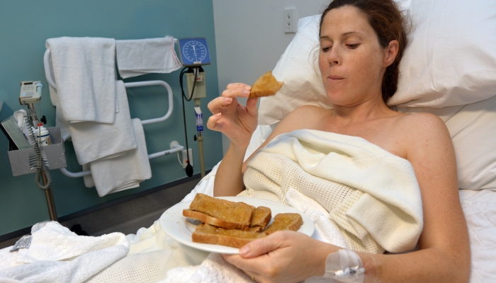 Hungry pregnant woman eats sweet food (peanut butter sandwiches) after childbirth.