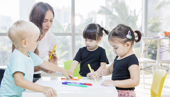 Kids learns to draw with their teacher in a daycare center.