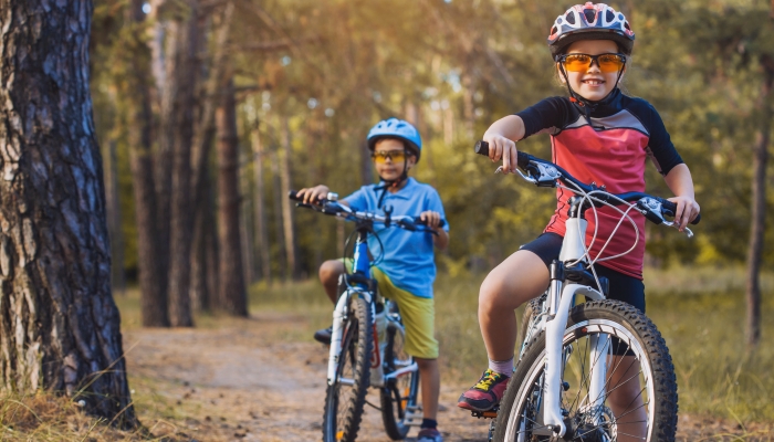 Kids on a bicycles in the sunny forest.