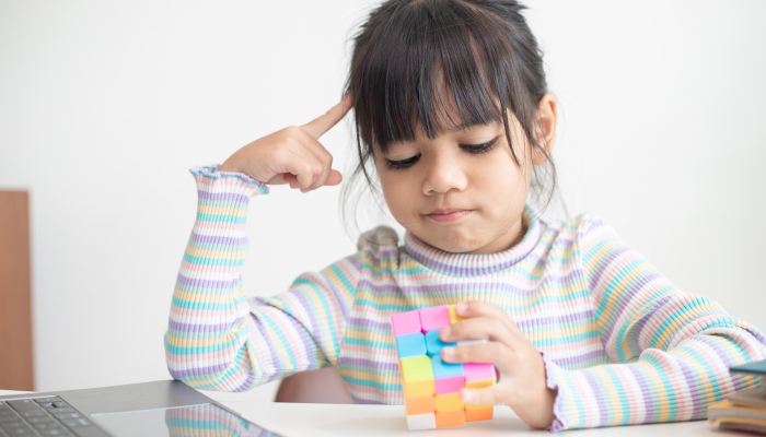 Little girl playing rubik's cube.