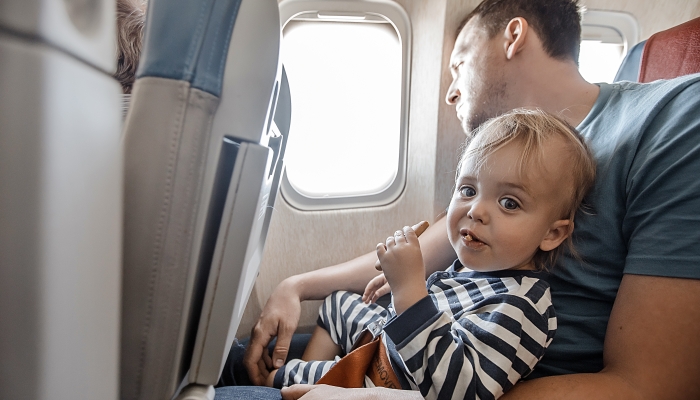 Man with little adorable boy eating snack sitting near window in plane.