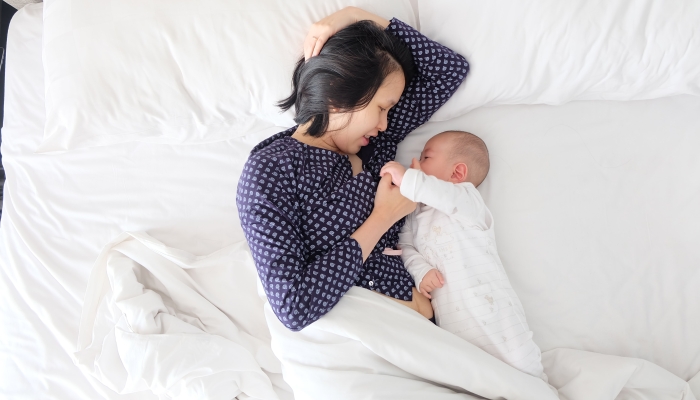 Mother beside a child wearing a sleep sack.