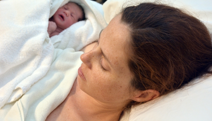 Mother with her newborn baby sleeping in bed after c-section.