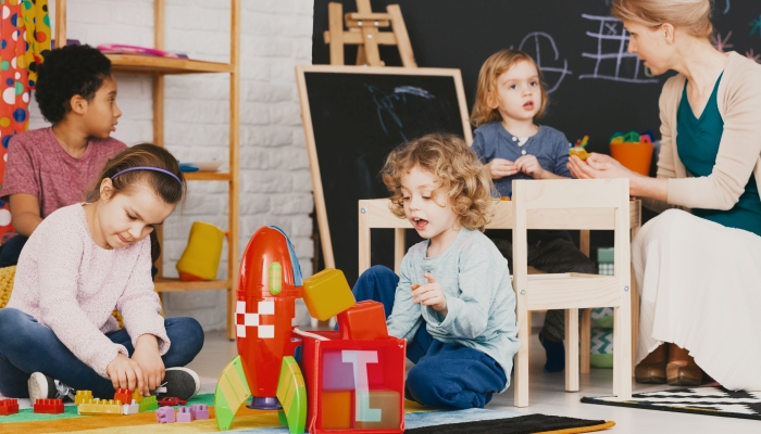 Multicultural kids playing together in daycare with big blackboard.