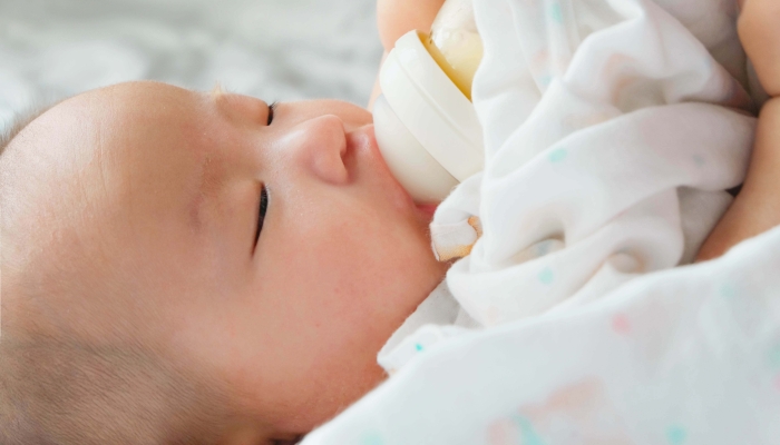 Portrait of a newborn Asian baby on the bed drinking milk.