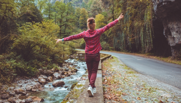 Pregnant girl enjoy the view of the mountains and the forest walking on the curb.