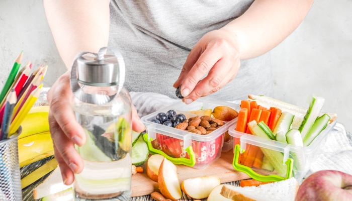 Pregnant woman preparing pack of snacks.