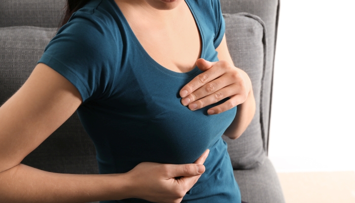 Pregnant woman touching her breast at home.