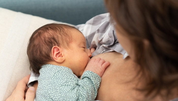 Top view of a young mother breastfeeding her newborn at home.