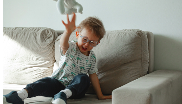 Autistic boy having a meltdown and throwing a toy.