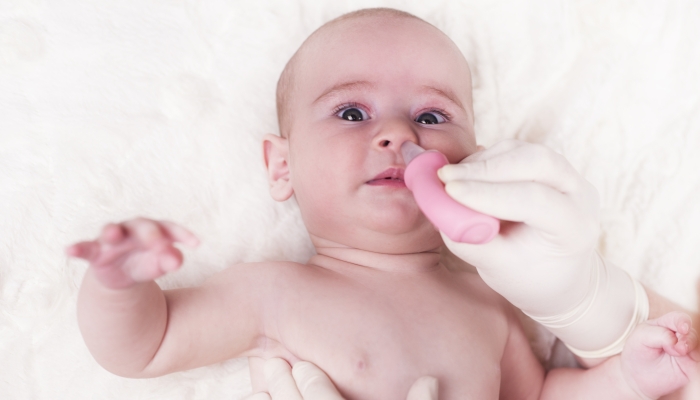 A child with a runny nose and a doctor uses a snot sucker.