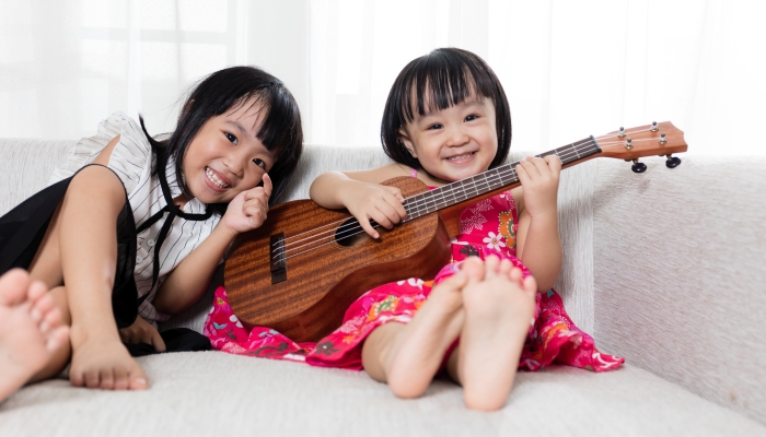 Asian Chinese little sister playing ukele.
