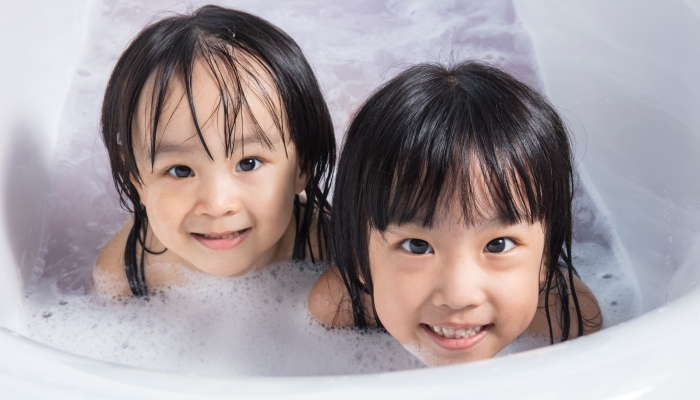 Asian little Chinese girls playing with water and foam.