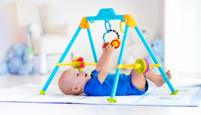 Baby boy on play mat reaching his toy.