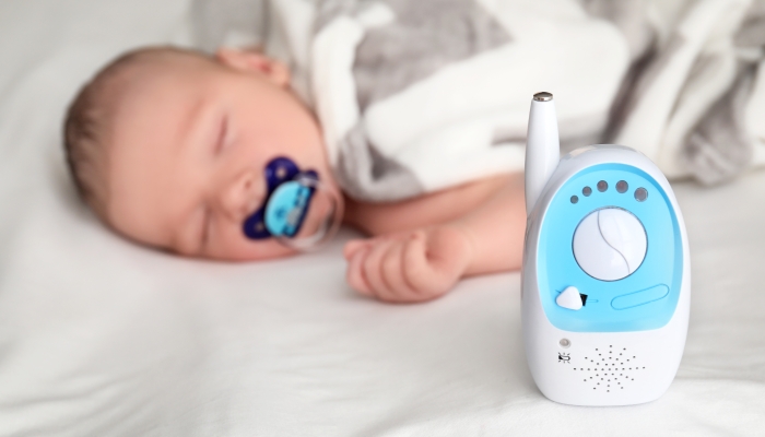 Baby monitor and sleeping child on bed,