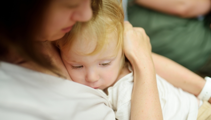 Cute funny toddler boy in his mothers arms.