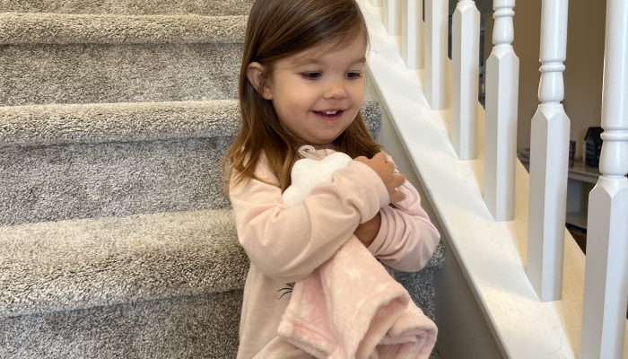 Cute girl holding a embracing a lovey in the stairs.