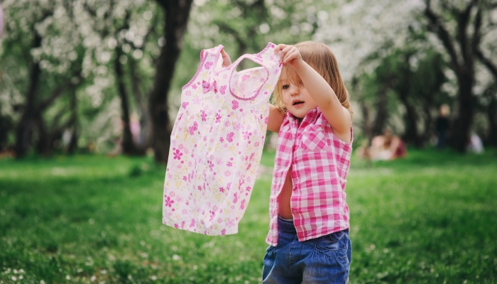 Cute little toddler girl getting dressed and changing clothes outdoor.