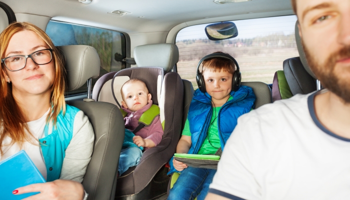 Happy young family, mother, father and two little boys having fun travelling by car.