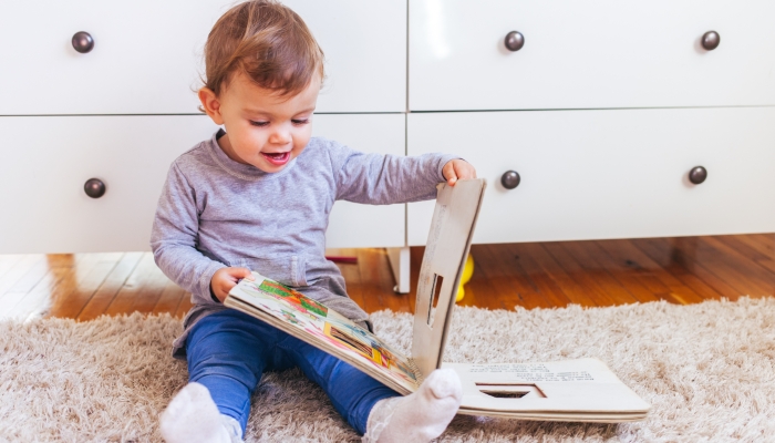 Little girl sitting on the floor and reading a book.