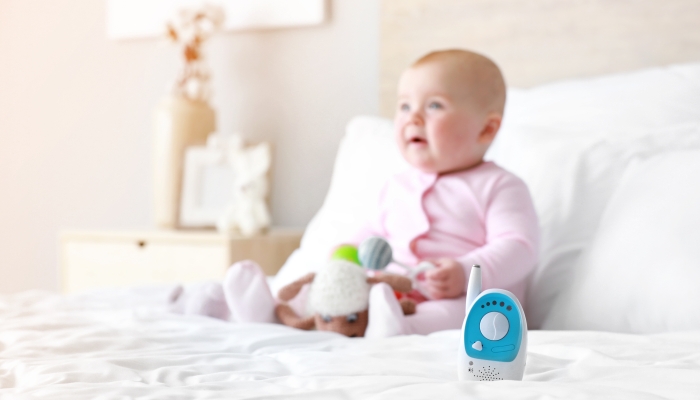 Modern baby monitor on bed with little child,